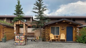 A rustic log cabin with a blue door labeled "Bush Pilot," a wooden deck, and a colorful climbing wall. - Bush Pilot Cabin-Modern Comfort in the Last Frontier (For families or casual travelers) (Tok)