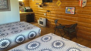 Ein gemütliches Blockhaus-Zimmer mit zwei Betten, einem Fernseher, einer Karte an der Wand und einer kleinen Küchenzeile.