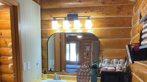 Ein Badezimmer in einer Holzhütte mit Waschbecken, Spiegel und einem kleinen schwarzen Geschirrspüler.