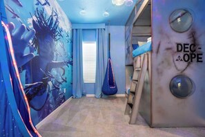 A room with a mural of underwater scenes, a bunk bed, a hanging chair, and a wall with a circular design.