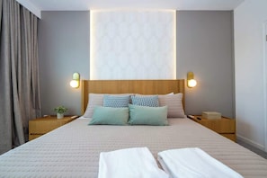 A neatly made bed with pillows, a bedside table with a lamp, and a wall-mounted light fixture. - Luxury Townhouse Near Universal At Paradiso Grande (Orlando)