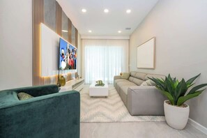 A modern living room with a sofa, a green armchair, a coffee table, and a potted plant.