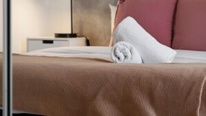 Una cama bien hecha con una toalla blanca, un edredón marrón y un cabecero con un panel gris.