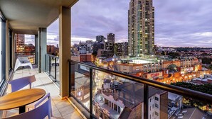 Un balcón con vista a la ciudad, incluyendo un edificio alto y una zona comercial.