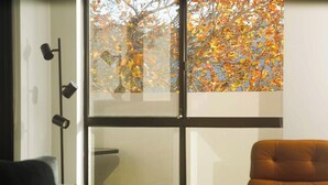 A room with a large window, a floor lamp, and a brown chair. - KozyGuru | Homebush West | Modern 2R Apt + Parking (Homebush West)