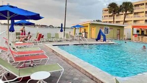 A swimming pool with lounge chairs and umbrellas, a street lamp, and a building with balconies in the background. - Sunset paradise, entire rental unit in Tampa,florida (Tampa)