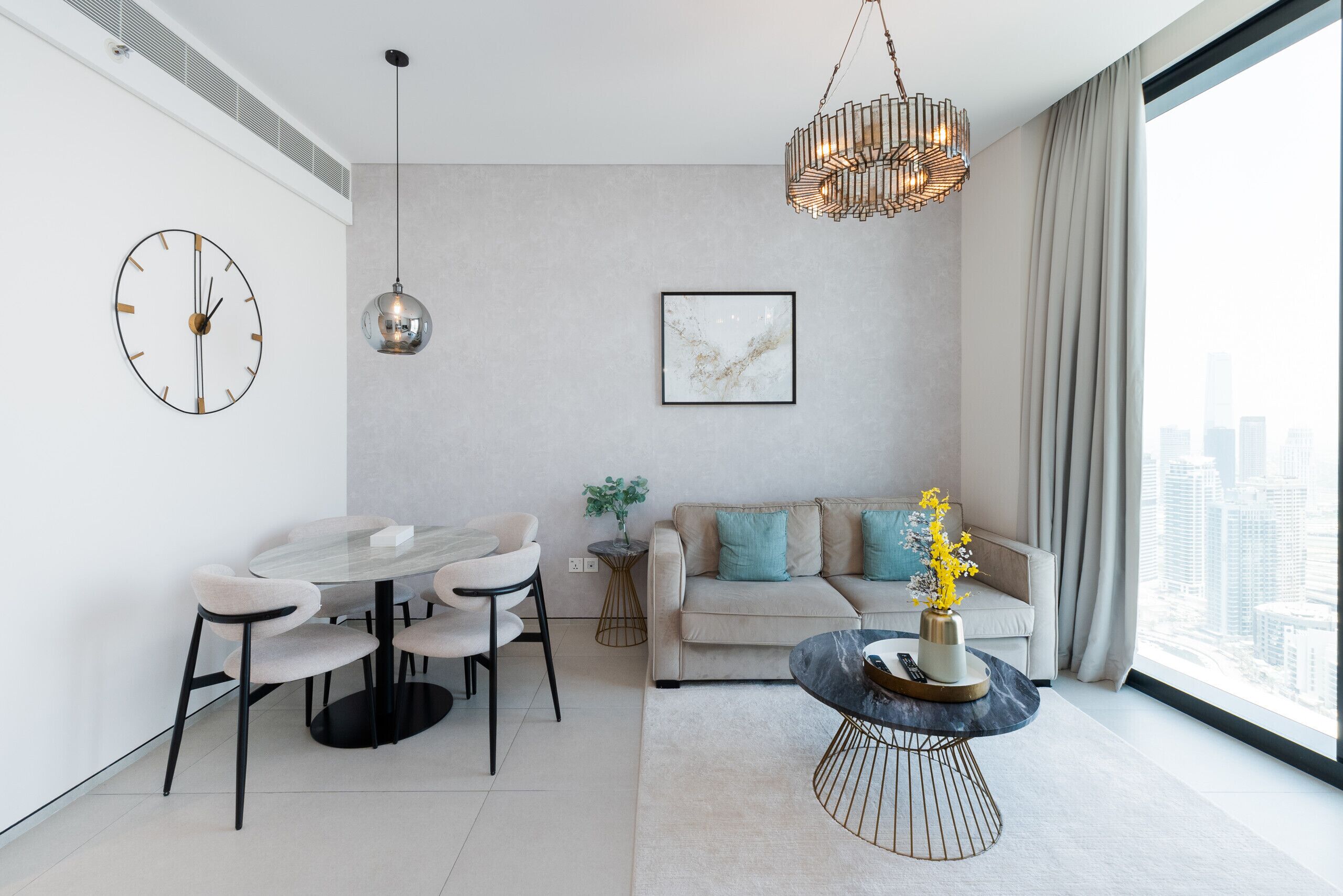 A modern living room with a dining area, a sofa, and a large window with a city view.