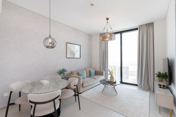 A modern living room with a dining table, sofa, and TV stand.