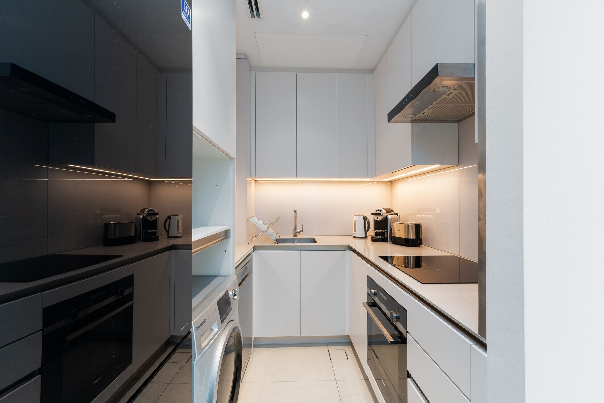 Een compacte keuken met moderne apparatuur, een ingebouwde wasmachine en een centraal keukenblok.