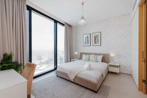 A modern bedroom with a large bed, bedside tables, a view of the city, and a large window.