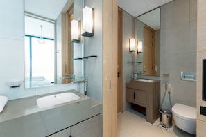 A modern bathroom with a large sink, mirror, and toilet.