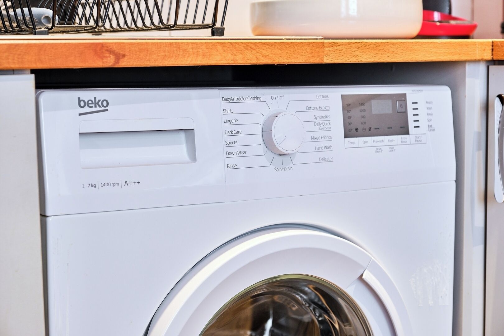 Vista frontal de una lavadora Beko blanca con panel de control, pantalla digital y función de centrifugado.