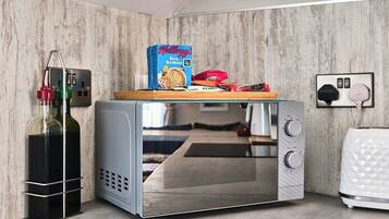 A compact kitchenette with a microwave, a small fridge, and a bottle of olive oil on the counter.