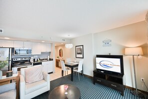 Un espacio habitable compacto con kitchenette, comedor y televisor.