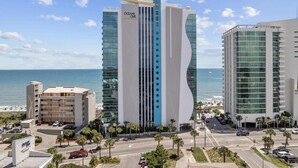 A modern hotel with a prominent 'OCEANS ONE' sign, featuring a unique curved facade and multiple balconies.