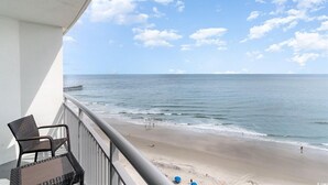 A balcony with a view of a beach and ocean.