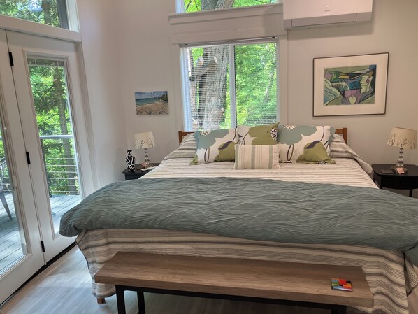 A bedroom with a bed, bedside tables, a bench, a painting, and a window with blinds.