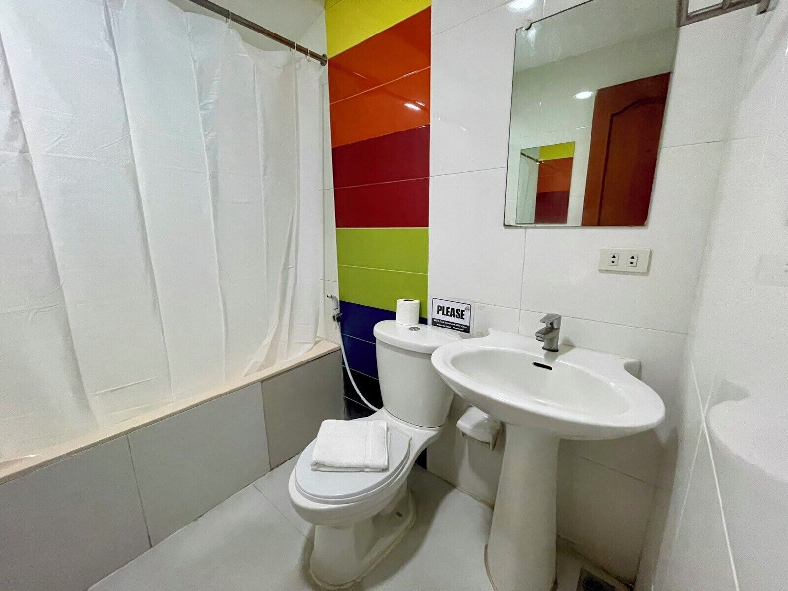 Un baño con inodoro blanco, lavamanos y cortina de ducha.