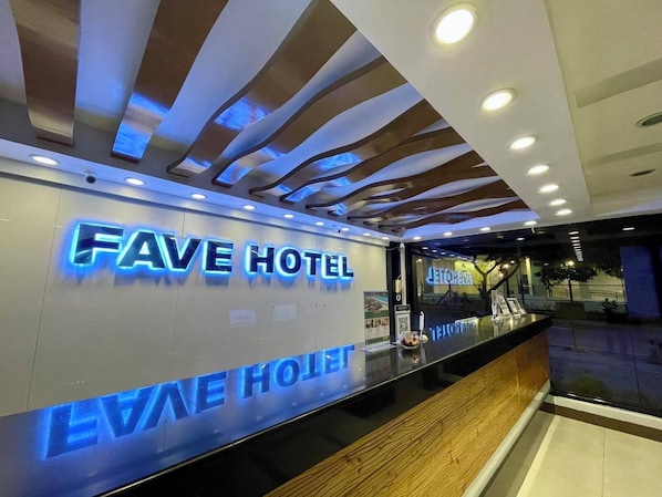 A reception desk with a sign that reads "FAVE HOTEL" and a glass partition. - Fave Hotel Angeles City formerly Hotel America (Angeles City)