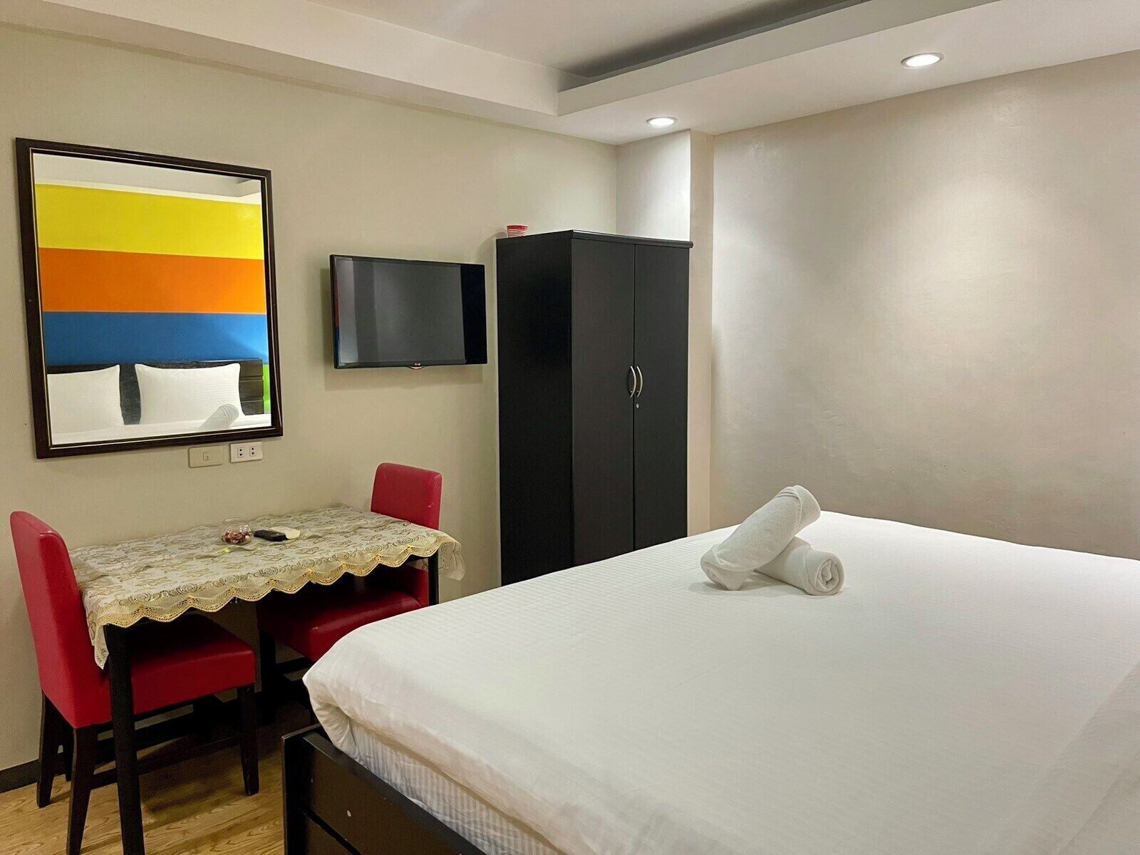 Una camera d'albergo con un letto, una scrivania con una sedia, una televisione e un armadio.