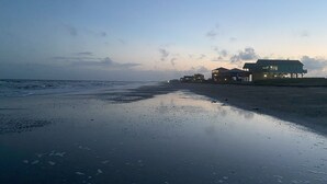 A beach with a row of wooden buildings, some with balconies, and a calm sea.