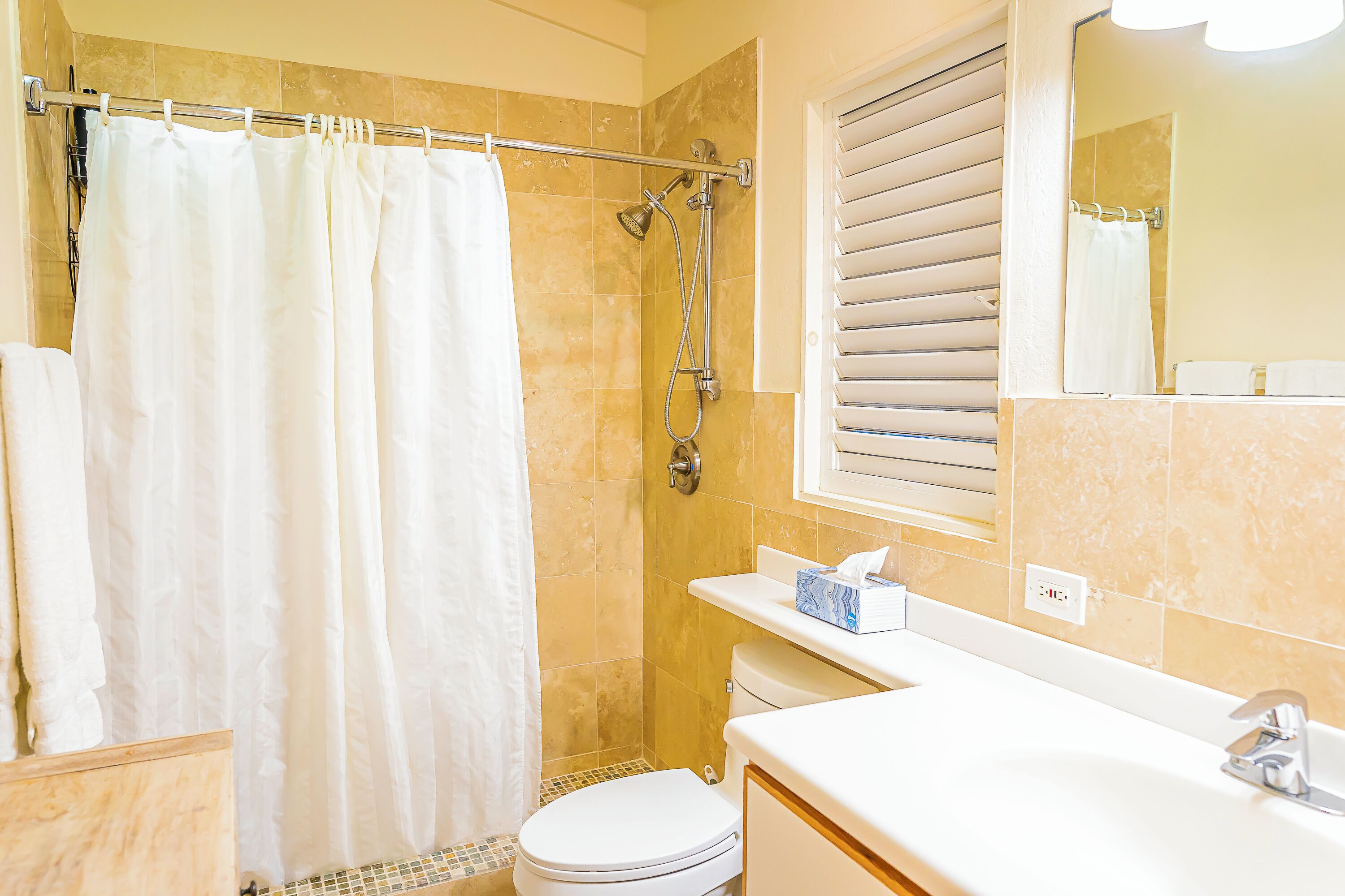 A bathroom with a shower, toilet, and sink.