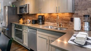 A modern kitchen with stainless steel appliances, a brick backsplash, and a clean, organized layout. - Charming 2-bedroom resort Located at Studio Ellis Square Savannah Georgia (Savannah)
