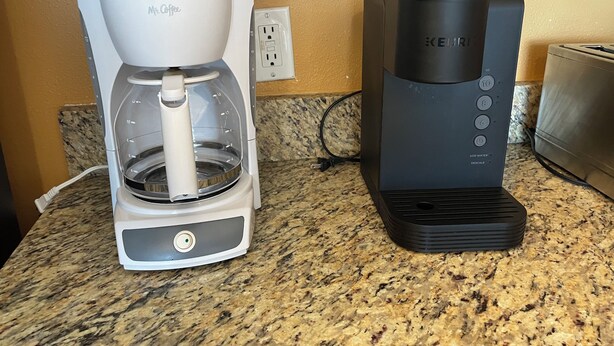 A coffee maker and a Keurig coffee machine on a granite countertop.