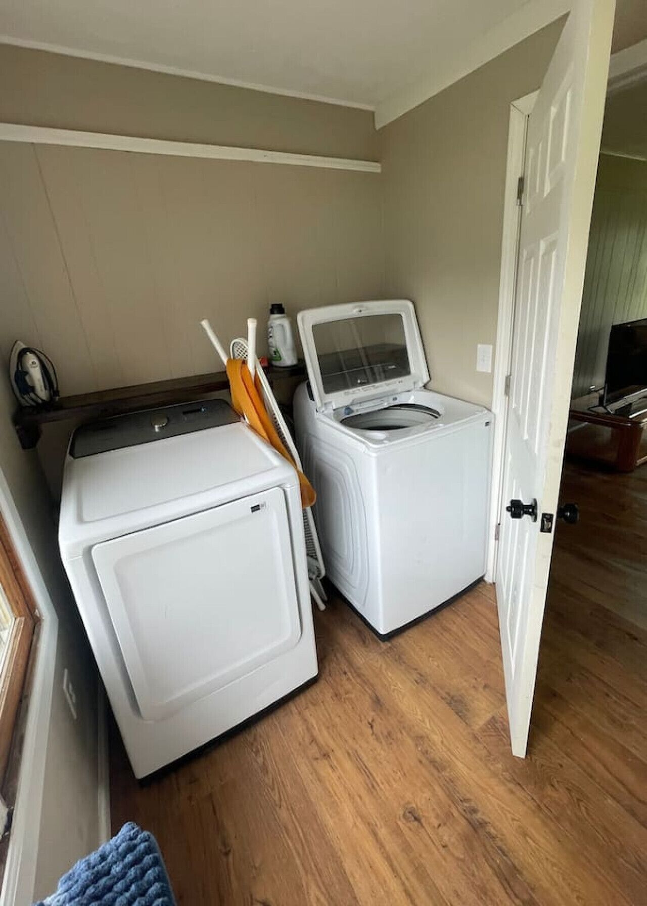 A laundry room with two washing machines, a dryer, and a door leading to another room.