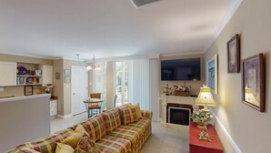 Una sala de estar con sofá, televisión, chimenea y comedor con mesa y sillas.