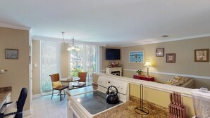 Una cocina con estufa, sillas, una mesa de comedor y un televisor.