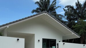 A modern house with a flat roof, a covered porch, and a glass door. - Passara Villas (Krabi)