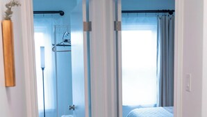 A bedroom with a bed, a window with curtains, a radiator, and a white door. - 18 min. to Detroit center - free parking on fenced premises (Ecorse)
