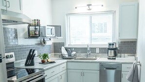 A modern kitchen with stainless steel appliances, white cabinets, and a tiled backsplash. - 18 min. to Detroit center - free parking on fenced premises (Ecorse)