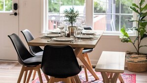 A dining area with a wooden table, black chairs, a woven pendant light, and a red patterned rug. - Family FUN! Luxury Touches, Mini Golf, Firepit, Fully Loaded (Thompson's Station)