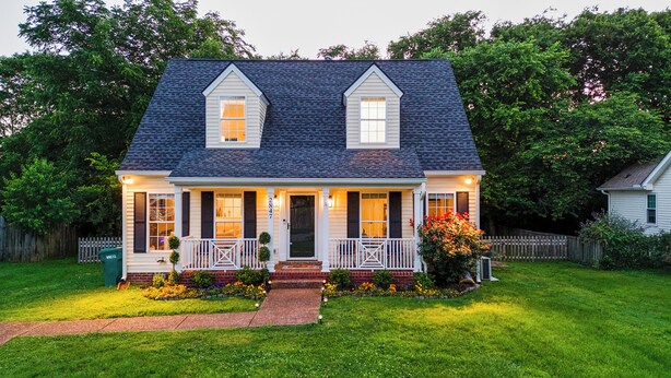 A two-story house with a front porch, a small front yard, and a wooden fence in the background. - Family FUN! Luxury Touches, Mini Golf, Firepit, Fully Loaded (Thompson's Station)