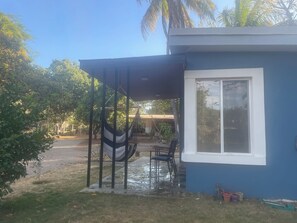 A small blue building with a covered porch, a hammock, and a chair. - Charming 2-bedroom cottage in beautiful Masaya with AC, WiFi (Masaya)