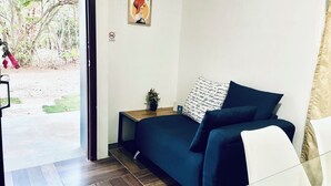 A room with a bed, a small table with a plant, a wall-mounted light switch, and a door leading outside. - Charming 2-bedroom cottage in beautiful Masaya with AC, WiFi (Masaya)