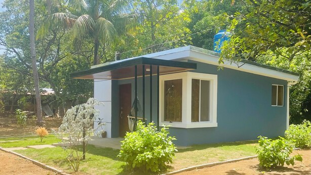 A small, modern house with a flat roof, large windows, and a small porch. - Charming 2-bedroom cottage in beautiful Masaya with AC, WiFi (Masaya)