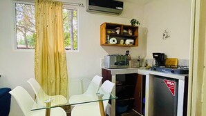 A compact kitchen with a glass table, white chairs, a microwave, a stove, and a shelf with kitchen items. - Charming 2-bedroom cottage in beautiful Masaya with AC, WiFi (Masaya)