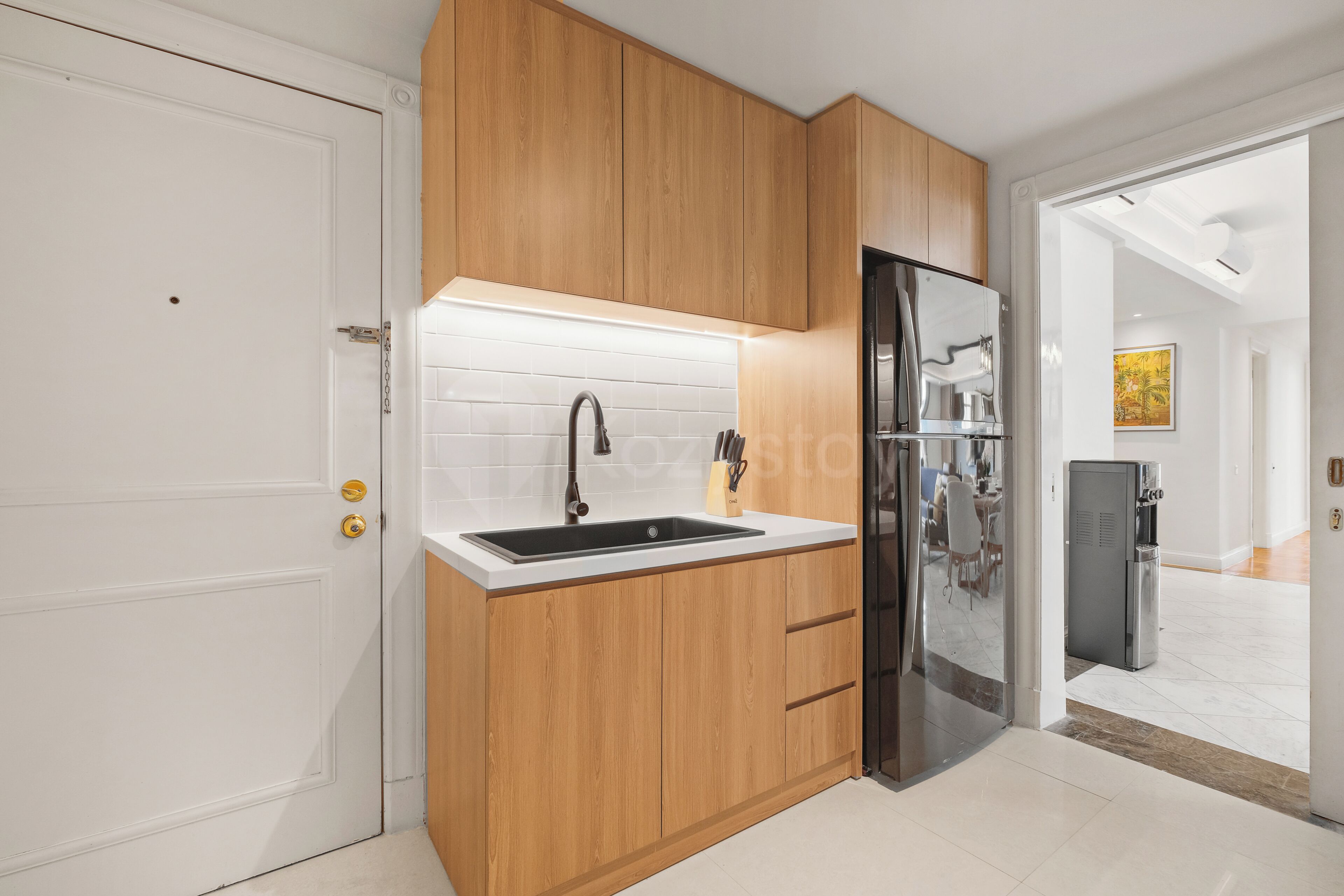 Una cocina moderna con armarios de madera, un lavamanos de acero inoxidable y un refrigerador empotrado.