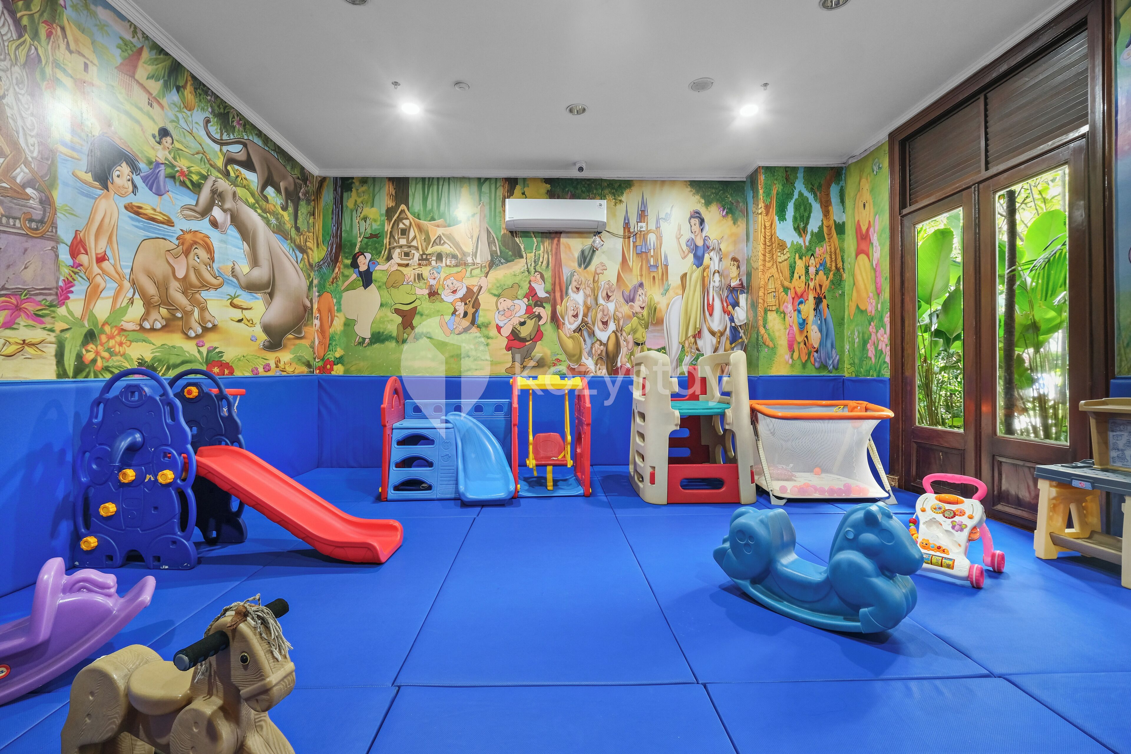 Un espace de jeux pour enfants agrémenté de peintures murales colorées, de toboggans et de diverses structures ludiques.