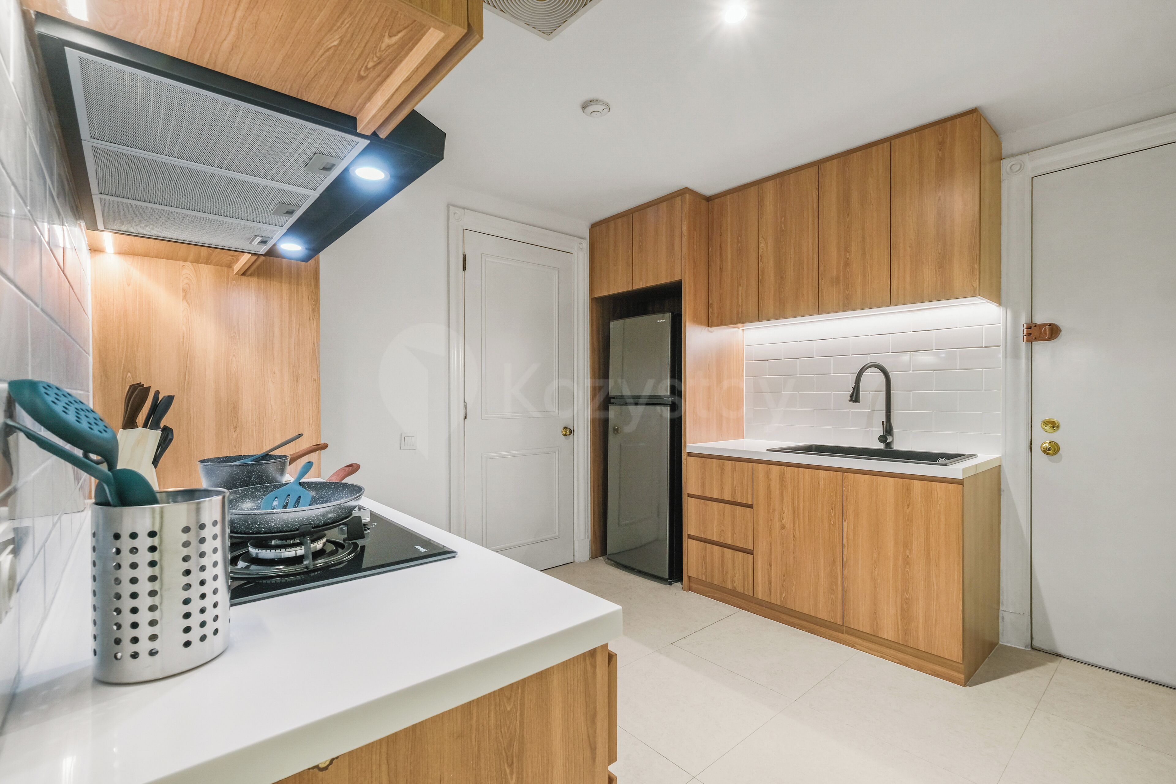 Una cucina moderna con mobili in legno, un lavello in acciaio inossidabile e un piano cottura a gas.