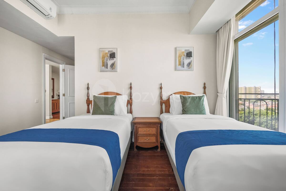 Une chambre d’hôtel avec deux lits, une table de chevet en bois et une grande fenêtre donnant sur un beau paysage.