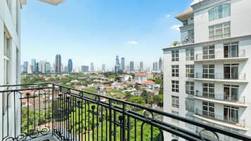 A balcony with a cityscape view, including high-rise buildings and residential areas.