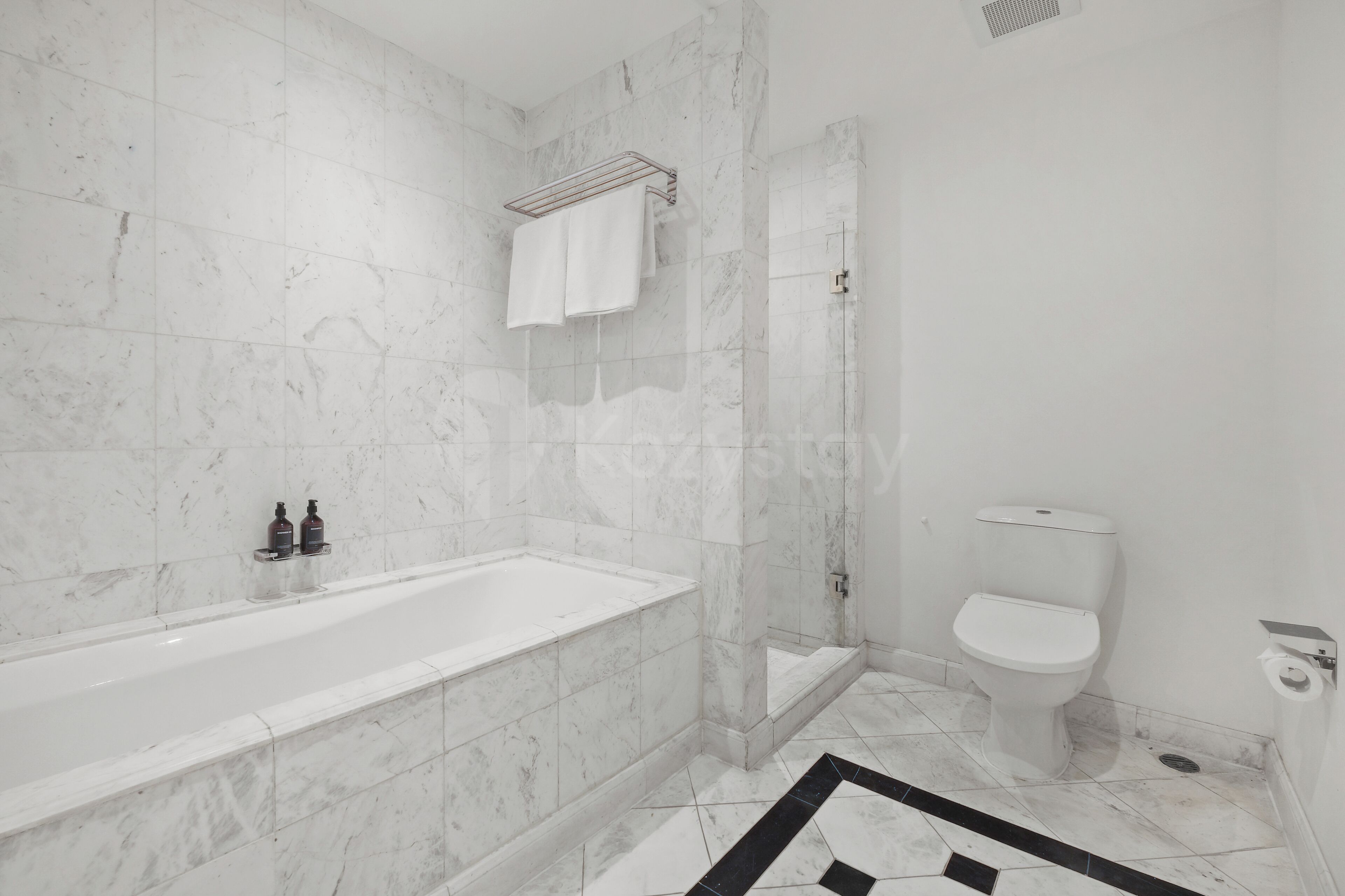 A bathroom with a bathtub, shower, toilet, and marble walls.