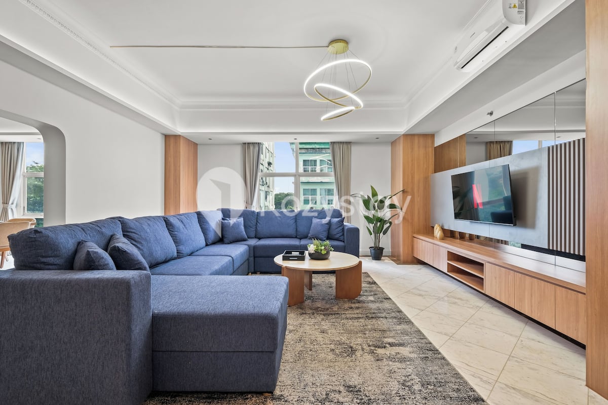 Un salon moderne avec un canapé d’angle, une table basse et un téléviseur à écran plat.
