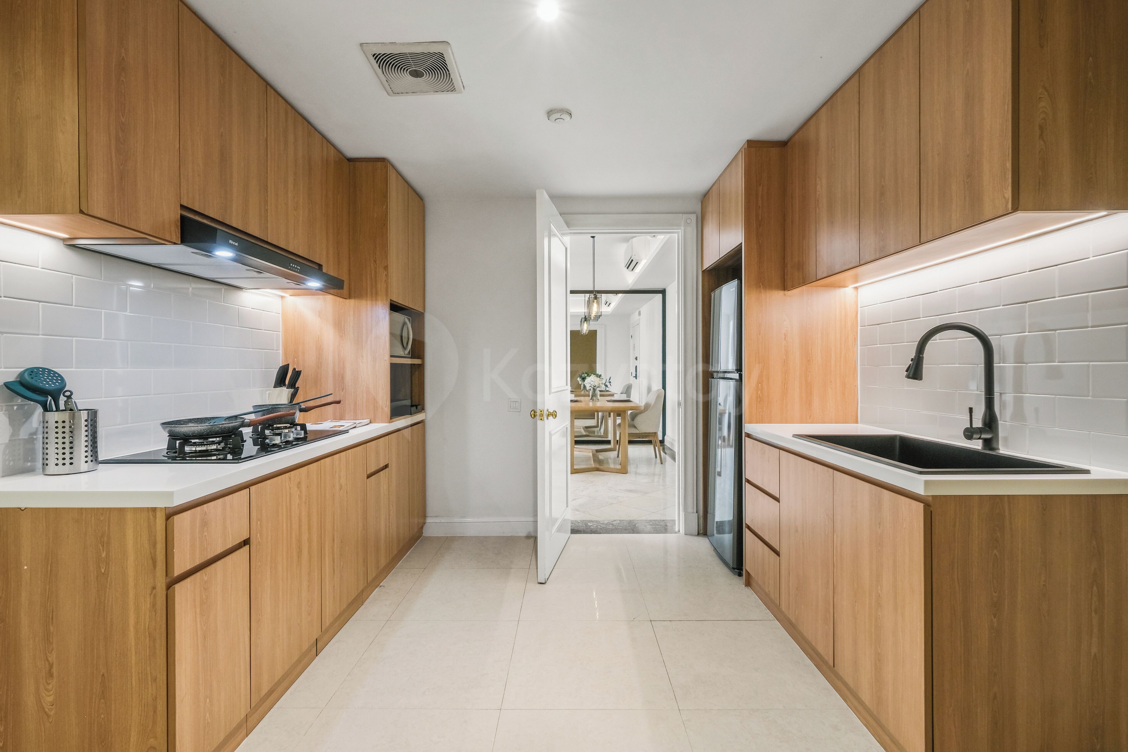 A modern kitchen with wooden cabinets, a gas stove, a sink, and a white-tiled backsplash.