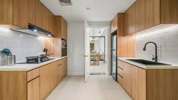 A modern kitchen with wooden cabinets, a gas stove, a sink, and a white-tiled backsplash.