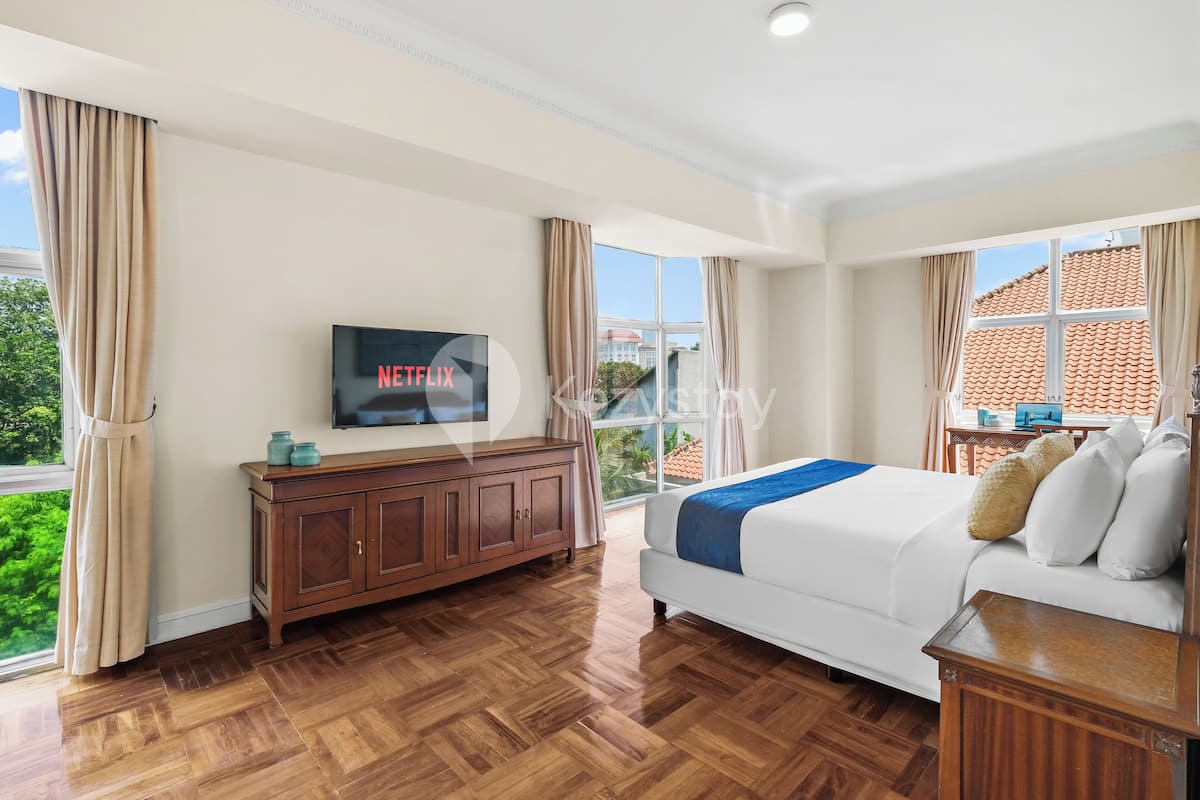 Une chambre d’hôtel avec un grand lit, un plancher en bois, un téléviseur fixé au mur et une vue sur l’extérieur.